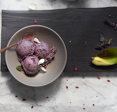 blueberry avocado nice cream in a gray bowl with an avocado peel off to the side