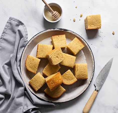 cornbread sliced on a platter waiting to be drizzled with honey