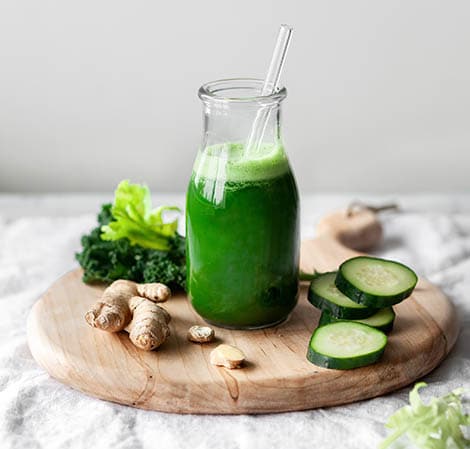 Bright green juice in a glass with a straw in it on a platter