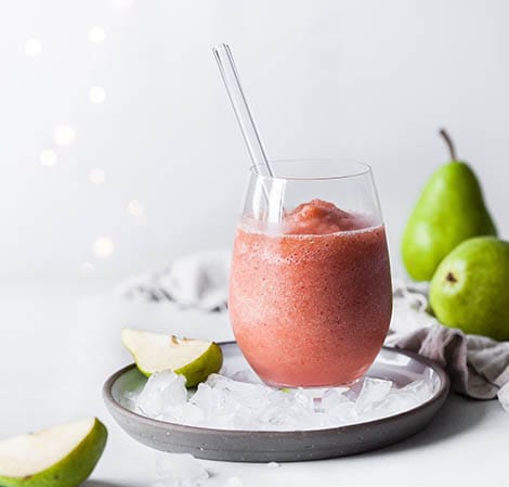 holiday fruit smoothie with a straw in it and pears in the background