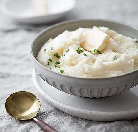 whipped and creamy mashed potatoes in a grey bowl with chives on top