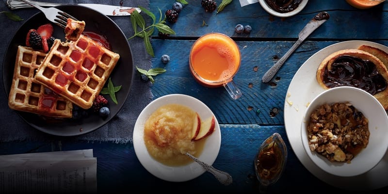 A table setting with waffles and orange juice