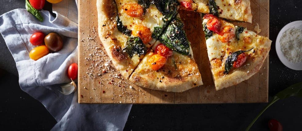 A veggie pizza with spinach and cherry tomatoes