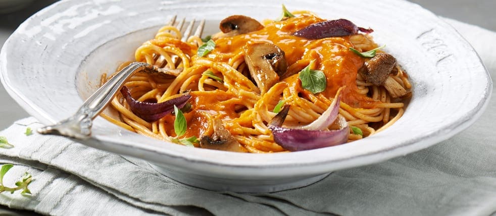 A bowl of spaghetti with tomato sauce, onions and mushrooms