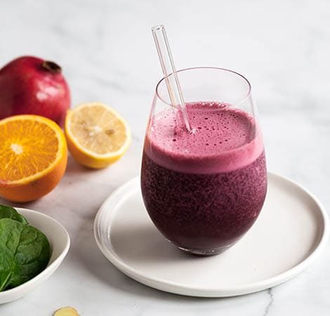 Purple smoothie in a glass with a clear straw in it