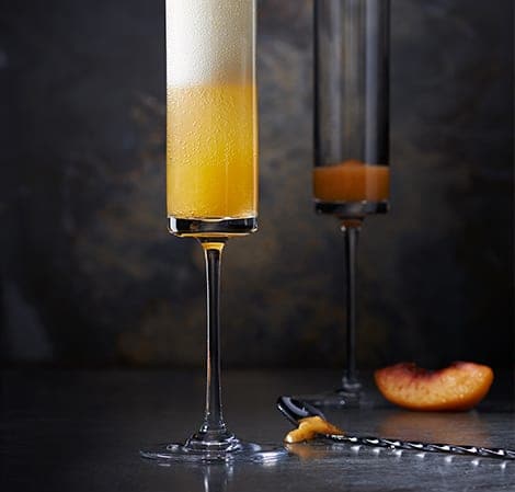Tall glass of peach bellini environment