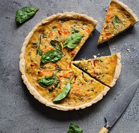 smoked salmon & spinach quiche with a slice taken out of it