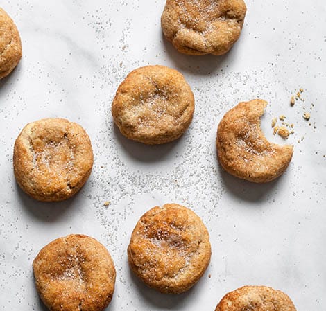 snickerdoodles on a counter with a bite taken out of one cookie