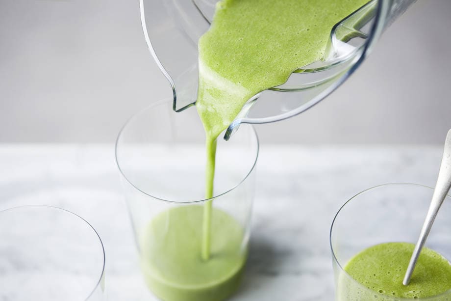 pouring green smoothie into cup